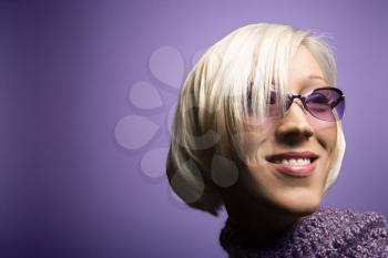 Royalty Free Photo of a Smiling Young Blond Woman on a Purple Background Wearing Sunglasses and a Scarf