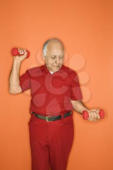 Mature adult Caucasian male lifting hand weights.