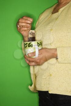 Royalty Free Photo of a Woman Dipping a Tea Bag into a Mug
