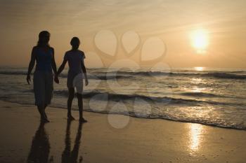 Royalty Free Photo of a Mother and Teenage Daughter Walking on the Beach at Sunset Holding Hands