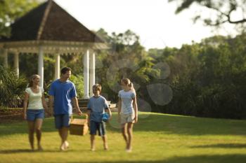 Royalty Free Photo of a Family of Four Walking in the Park Carrying a Picnic Basket