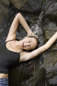 Royalty Free Photo of a Woman Standing Under a Waterfall Laughing