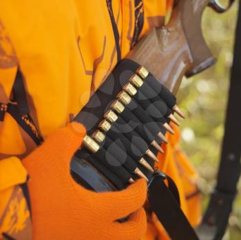 Close-up of hunter removing bullet from ammo holder on rifle.