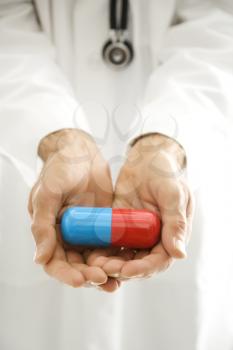 Royalty Free Photo of a Doctor Holding Out an Over Sized Medical Pill