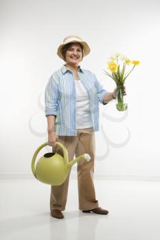 Royalty Free Photo of a Middle Aged Woman Holding Flowers and a Watering Can