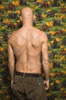 Portrait of a shirtless Mid-adult Caucasian male with back towards viewer.