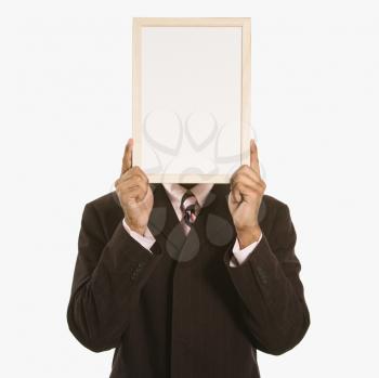 African American man holding blank sign over his face standing against white background.