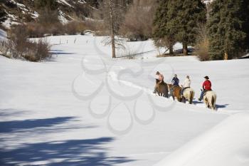 Royalty Free Photo of a Group of People Horseback Riding in Snow Covered Landscape in Colorado, USA
