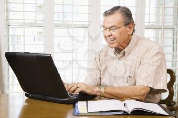 Royalty Free Photo of an Older Man Typing on a Laptop