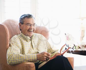Royalty Free Photo of a Mature Man Sitting in a Chair Reading a Book
