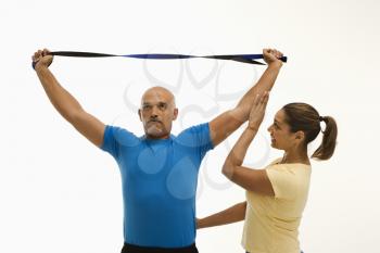 Royalty Free Photo of a Woman Assisting a Man With a Stretching Band