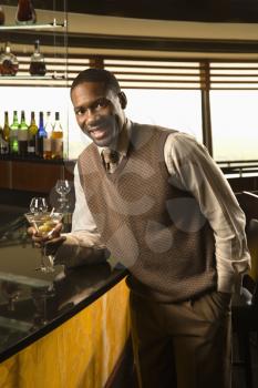 Royalty Free Photo of a man leaning on bar with martini