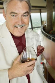 Royalty Free Photo of a Mature Man in a Suit Holding a Snifter of Brandy Smiling