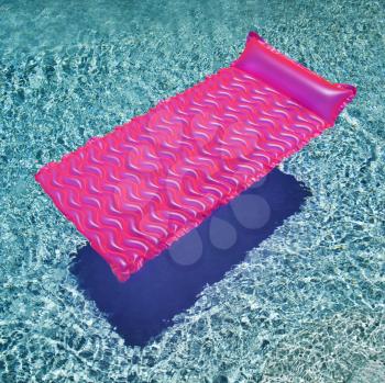 Pink float in empty swimming pool with rippling blue pool.