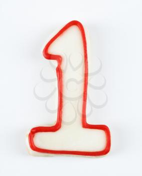 Sugar cookie in the shape of a number one outlined in red icing.