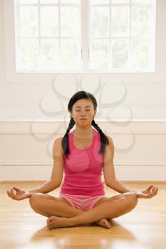 Royalty Free Photo of a Woman Sitting in a Lotus Position Practicing Yoga With Eyes Closed