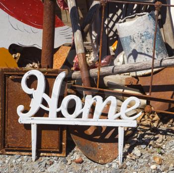 Metal figure with word 'Home' leaning against junk.