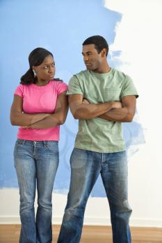 Royalty Free Photo of a Couple Glaring at Each Other Next to a Half-Painted Wall