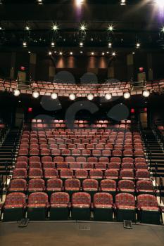 Rows of empty seats in theater seen from stage. Vertical shot.