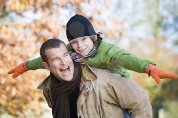 Royalty Free Photo of a Man Giving a Boy a Piggyback Ride