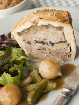 Royalty Free Photo of Pork Black Truffle and Pistachio Pie with Glazed Button Onions and Cornichons
