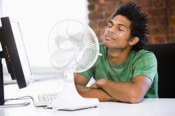 Royalty Free Photo of a Man Cooling Off by a Fan