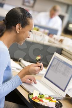 Royalty Free Photo of a Woman Eating a Salad at Her Desk