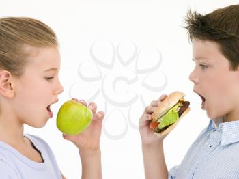 Royalty Free Photo of a Boy Eating a Cheeseburger and a Girl Eating an Apple