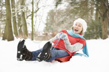 Senior Woman Sledging Through Snowy Woodland