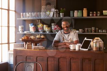 Portrait Of Male Coffee Shop Owner Standing Behind Counter