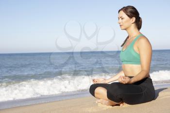 Young Woman In Fitness Clothing Meditating On Beach