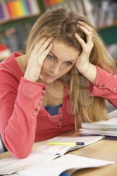Stressed Female Teenage Student Studying In Classroom