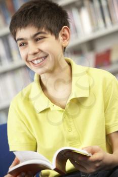 Male Teenage Student In Library Reading Book