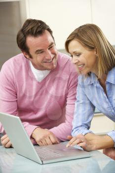 Mature couple using laptop in domestic kitchen