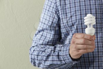 Cropped Studio Shot Of Man Holding Energy Saving Lightbulb