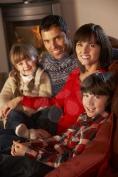 Portrait Of Family Relaxing On Sofa By Cosy Log Fire