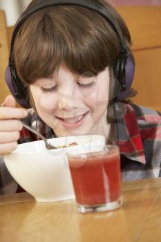 Boy Listening To MP3 Player Whilst Eating Breakfast