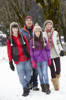 Teenage Family Walking Along Snowy Street In Ski Resort
