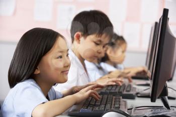 Female Pupil Using Keyboard During Computer Class In Chinese School Classroom