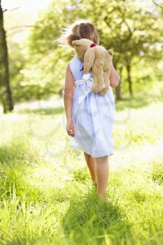 Young Girl Walking Through Summer Field Carrying Teddy Bear