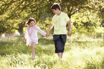 Boy And Girl Walking Through Summer Field Together