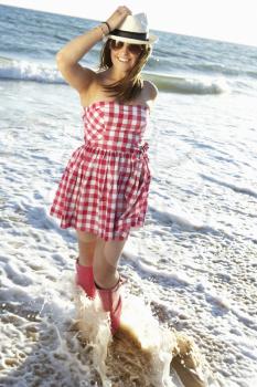 Teenage Girl Wearing Wellington Boots Splashing In Sea On Beach Holiday