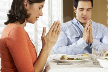 Couple Saying Grace Before Meal At Home