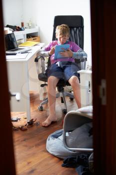 Boy Using Digital Tablet In Bedroom