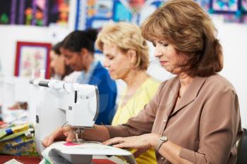 Group Of Women Using Electric Sewing Machines In class