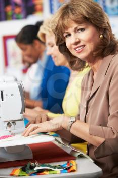 Group Of Women Using Electric Sewing Machines In class