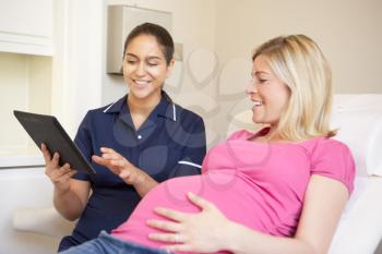 Nurse Using Digital Tablet In Meeting With Pregnant Woman