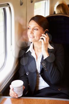 Female Commuter With Coffee On Train Using Mobile Phone