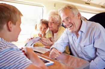 Grandparents And Grandchildren Relaxing On Train Journey