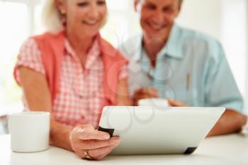 Smiling Middle Aged Couple Looking At Digital Tablet